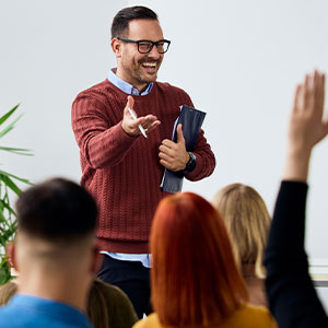 Ein Dozent spricht vor einer Gruppe und nimmt eine Wortmeldung entgegen &ndash; eine lebendige Szene aus Weiterbildung und gemeinsamem Lernen.