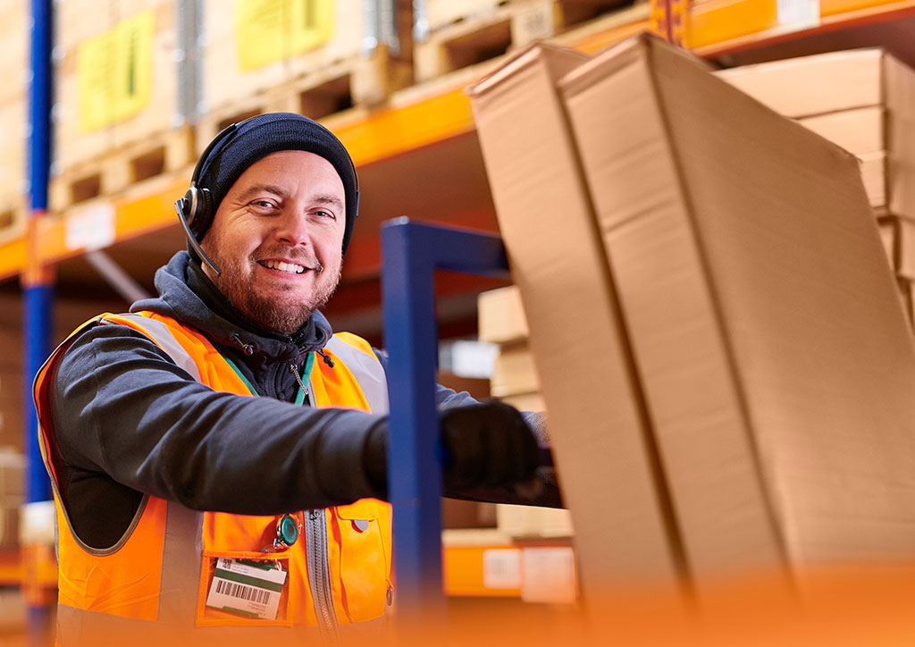 Lagerlogistik Job &ndash; Mitarbeiter verpackt Ware und kommuniziert per Headset